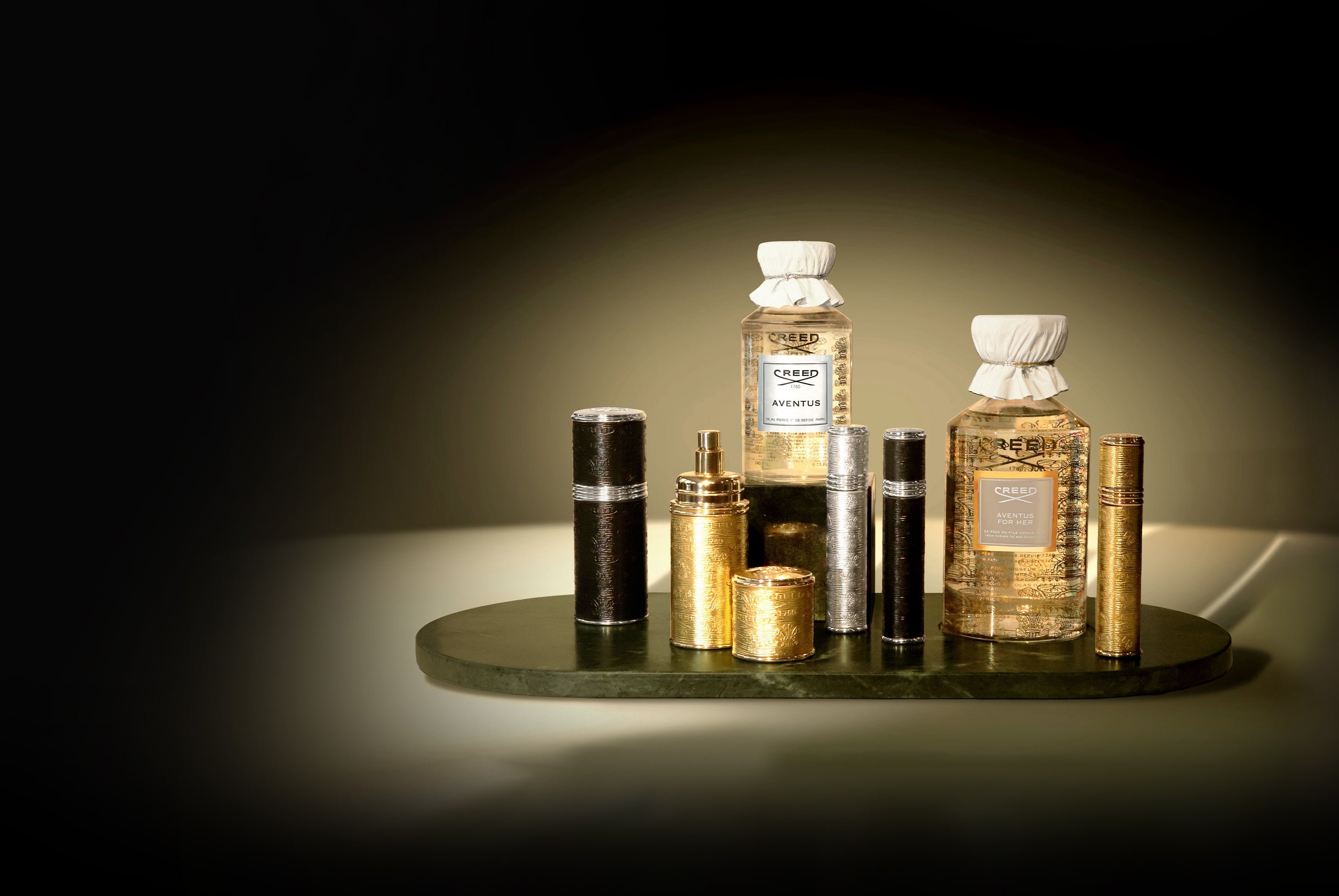Collection of perfume bottles on a dark surface with a dark background