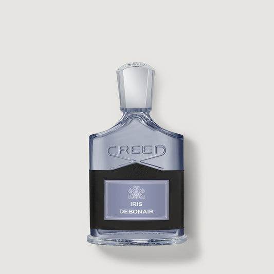 Iris Debonair Creed Debonair Iris perfume bottle with a clear glass body, silver cap, and a black label with a light purple panel, centered on a light gray background.