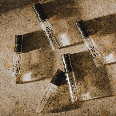 Complimentary Samples Creed fragrance sample vials elegantly arranged on a textured surface, highlighting exclusive member benefits.