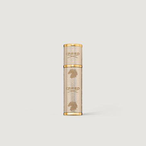 Creed gold leather 5ml perfume atomizer on a light gray background