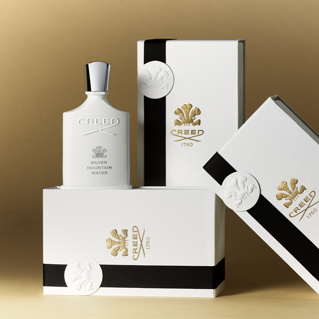 Creed Silver Mountain Water perfume bottle and packaging on a gold background