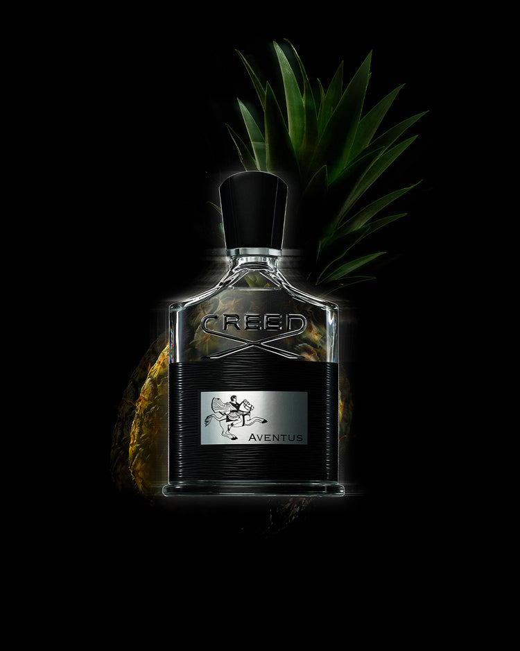 Creed Aventus perfume bottle with fresh pineapple highlighting its fruity fragrance notes 