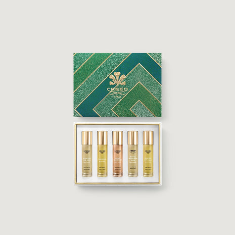 Set of Creed perfume bottles in a decorative box on a light gray background