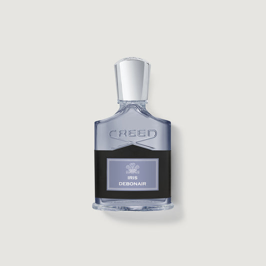 A bottle of Creed Iris Debonair perfume with a clear glass body, a black label, and a silver cap, centered on a light gray background.