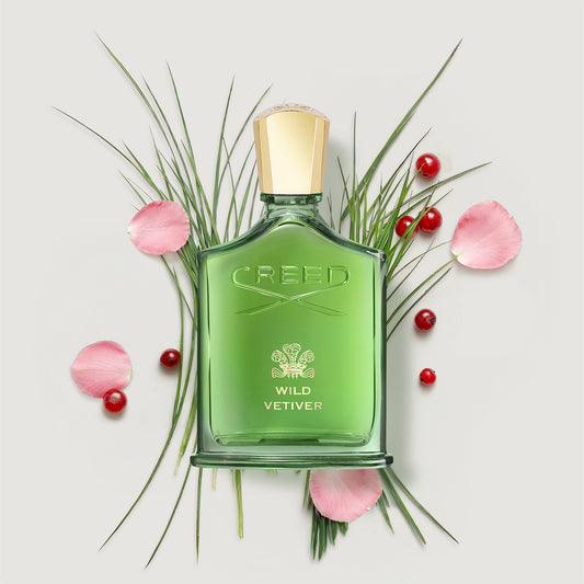 Green Creed Wild Vetiver perfume bottle with flowers and berries on a light background