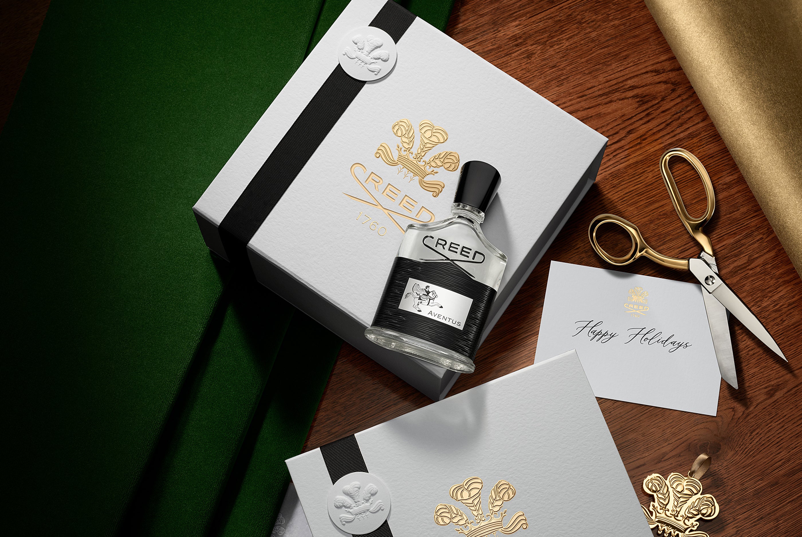 Creed perfume bottle with packaging and stationery on a wooden surface