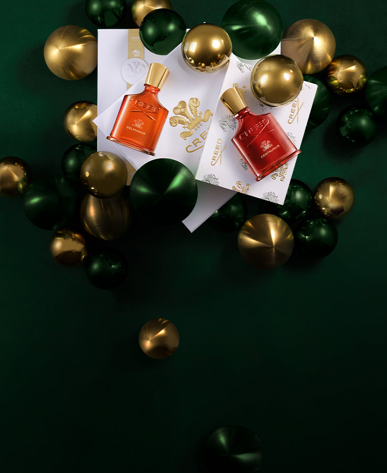 The Amber Duo - Centaurus and Delphinus bottles on top of creed gift box with gold and green ornaments around.