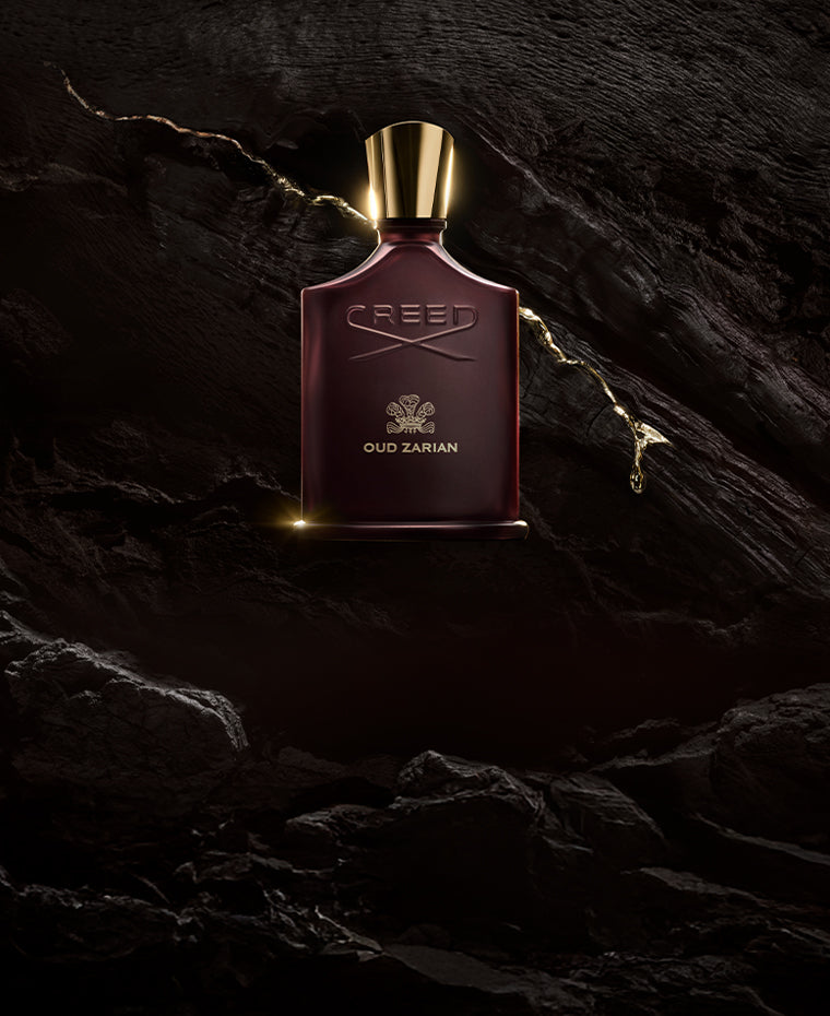 Creed Oud Zarian perfume bottle on a dark stone background with gold liquid line