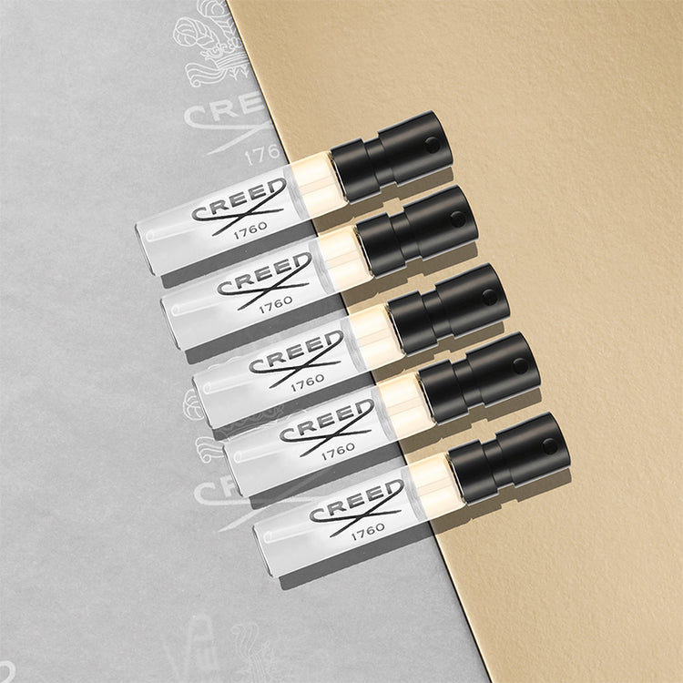 Five Creed perfume bottles on a gray and beige background