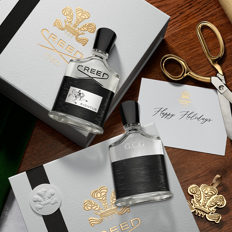 Two Creed perfume bottles on a wooden surface with decorative elements.