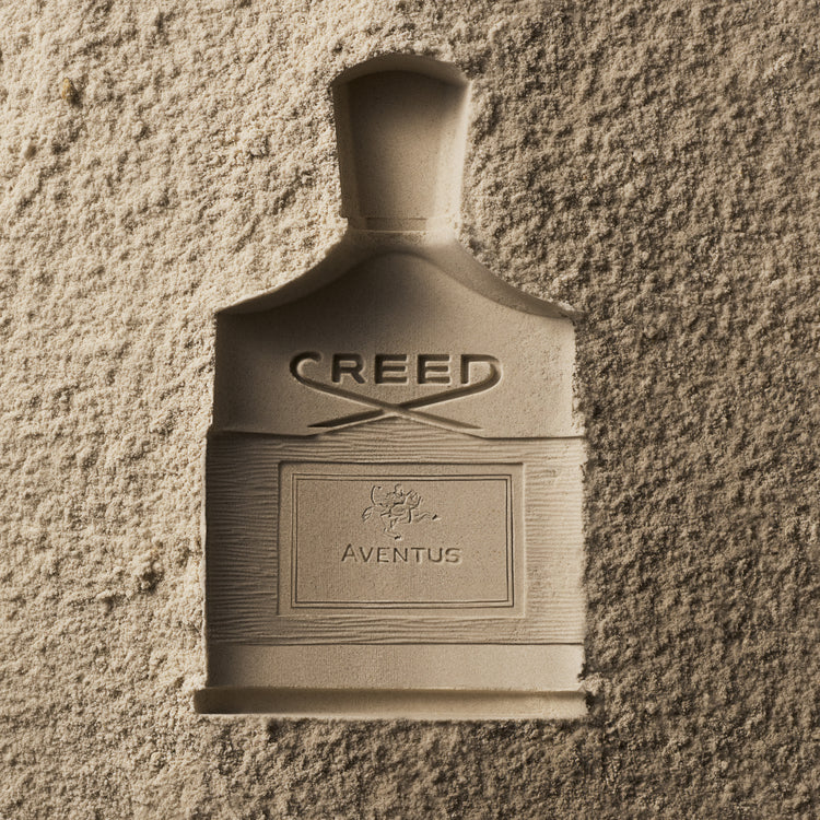Creed Aventus perfume bottle on a textured wall