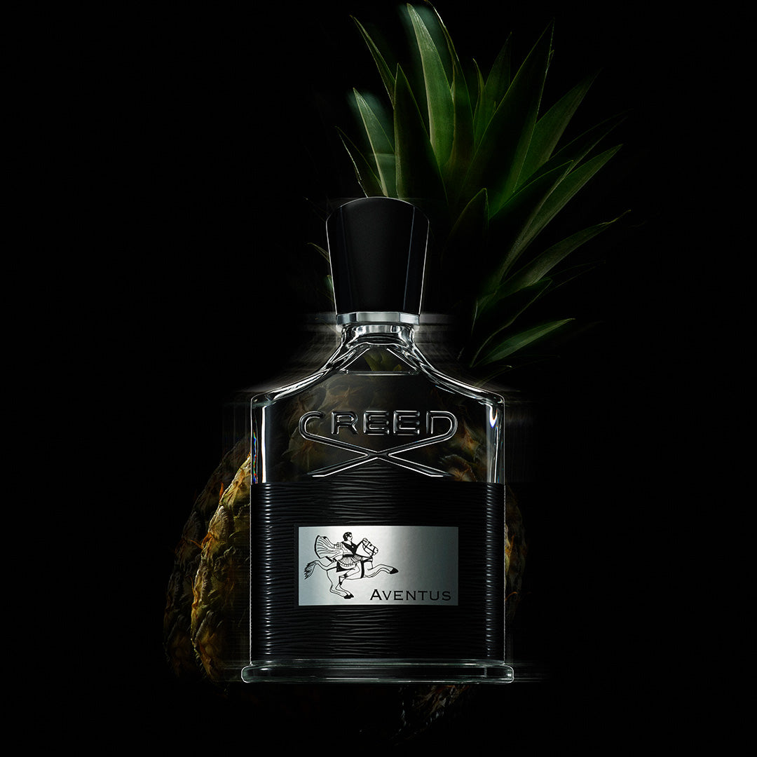 Creed Aventus perfume bottle with fresh pineapple highlighting its fruity fragrance notes 