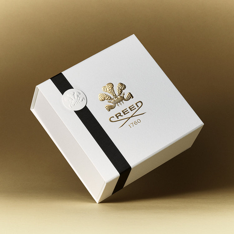 White box with black ribbon and Creed logo on a beige background