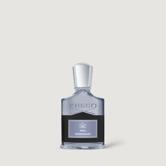Creed Debonair Iris Eau de Parfum bottle, featuring a clear glass body with a dark liquid base, a silver cap, and a black label with a light purple accent, set against a solid light gray background.
