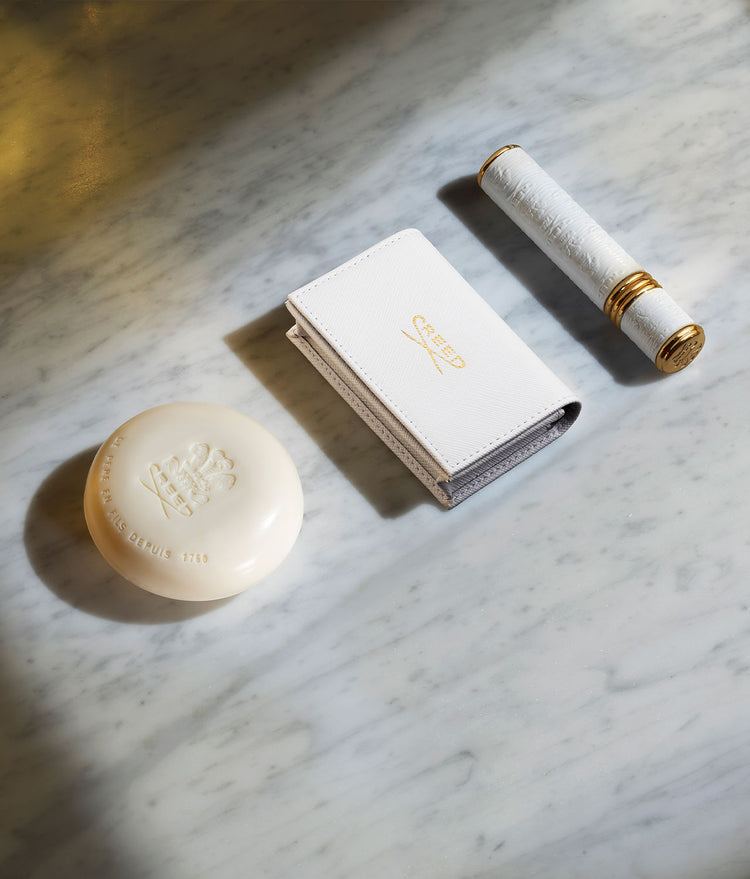 Soap, the White Leather Wallet, and a 10ml white with gold trim atomizer on a white marble top