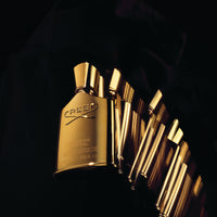 Gold Creed perfume bottles on a black background