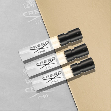 Three Creed perfume bottles on a gray and beige background