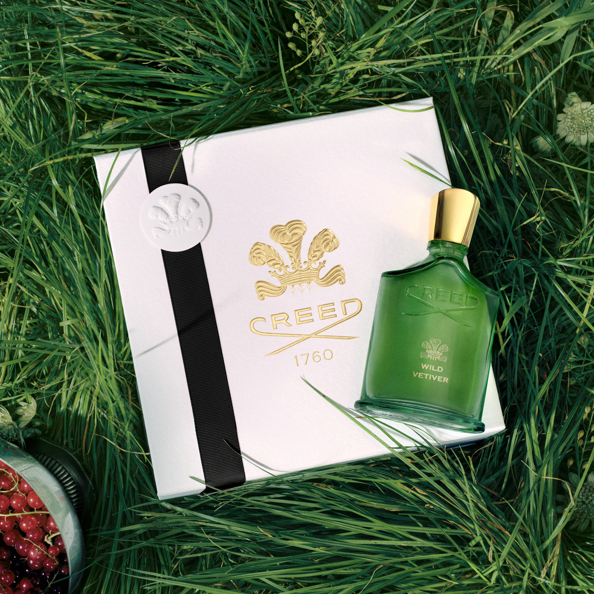 Green Creed perfume bottle with packaging on grass