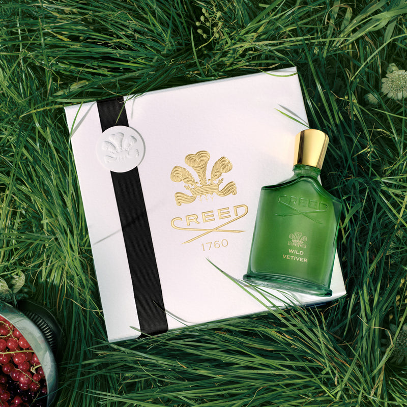 Green Creed perfume bottle with packaging on grass