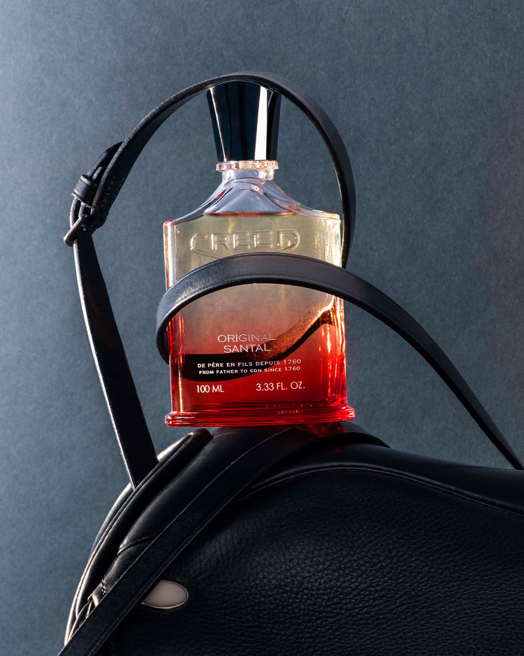 Creed Original Santal Bottle is on top of the leather bag.