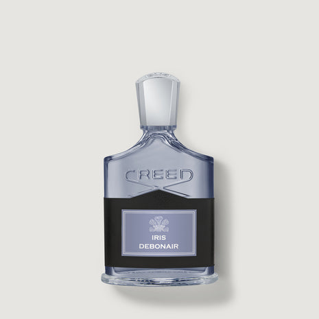 Creed Debonair Iris perfume bottle with a clear glass body, silver cap, and a black label with a light purple panel, centered on a light gray background.