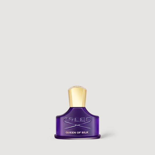 Creed Queen of Silk fragrance bottle in deep purple glass with a metallic gold cap, centered against a light gray background.