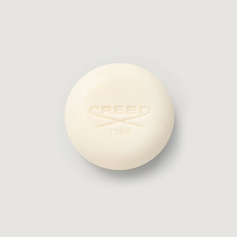 Cream-colored bar of soap with 'CREED' branding on a light gray background