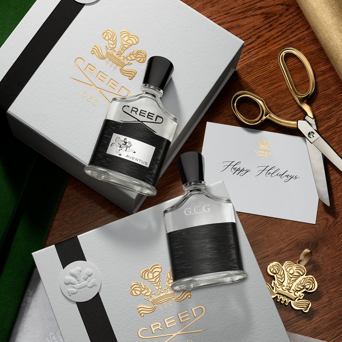 Two Creed perfume bottles on a wooden surface with decorative items.