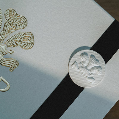Elegant gift-wrapping details showing a textured paper with gold embossed elements and a black ribbon